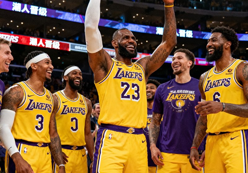 NBA季后赛战报配图，湖人队球员在斯台普斯中心庆祝晋级，勒布朗·詹姆斯高举双手